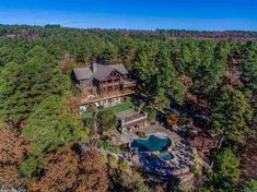 an aerial view of a large home surrounded by trees and water in the middle of a forest