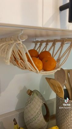 some oranges and bananas are in a hammock hanging from the ceiling above a kitchen counter