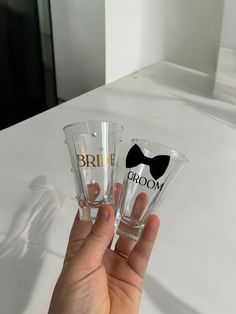 two bride and groom shot glasses with bow ties on them, sitting on a table