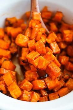 a spoon in a bowl filled with sweet potatoes