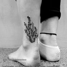 a black and white photo of a person's foot with a coral tattoo on it