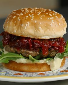 a hamburger with meat, cheese and lettuce on a bun sitting on a plate