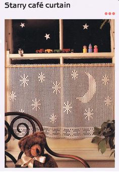 a teddy bear sitting on a chair in front of a window with stars and moon curtains