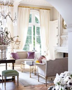 a living room filled with lots of furniture and a chandelier hanging from the ceiling