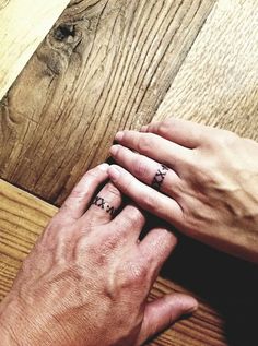 two hands holding each other on top of a wooden floor next to a piece of wood