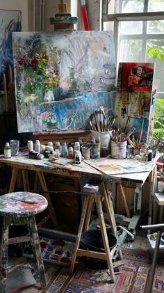 an artist's studio with easel, stools and paintings