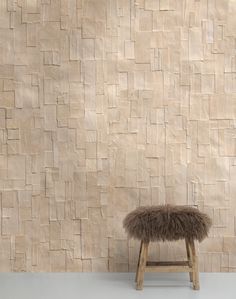 an animal fur stool in front of a wall with a stone pattern on the side