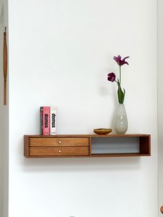 a vase with flowers on top of a shelf next to a chair and bookcase