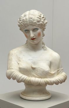 a white statue with blue eyes holding a bowl in it's hands and looking at the camera