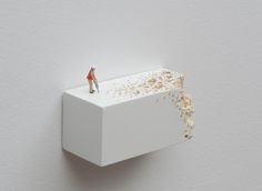 a miniature man standing on top of a block of white paper with brown sprinkles