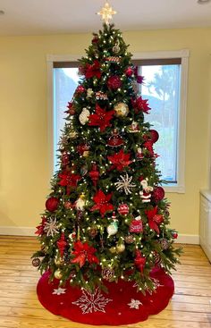 a christmas tree decorated with red and silver ornaments is in the corner of a room