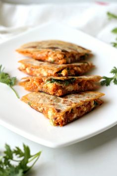 three pieces of food on a white plate with parsley around it and garnishes