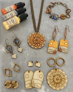 an assortment of wooden jewelry and paint on a counter top next to bottles of ink