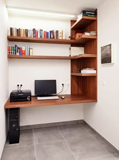 a desk with a computer on top of it in front of a book shelf filled with books