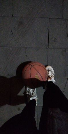 a person holding a basketball in their hand on the ground with his feet propped up