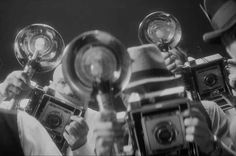 a group of people holding up some old fashioned camera's in front of them