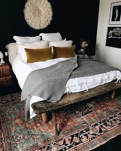 a bed with pillows and blankets on top of it next to a rug in a room