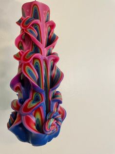 a multicolored candle hanging from a hook on a wall in the shape of a tree