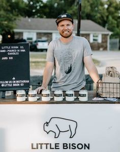 a man standing behind a table with jars on it