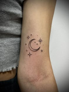 a woman's arm with a small crescent and stars tattoo on the left side