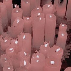 many pink candles are lined up on the floor in front of each other, with one lit candle surrounded by smaller ones