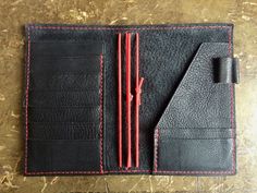 a black leather wallet with red stitching on the front and back sides is open