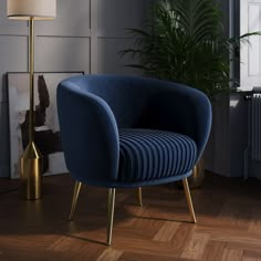 a blue chair sitting on top of a hard wood floor next to a tall plant