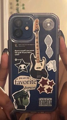 someone holding up their phone case with stickers on it