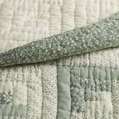 a close up of a quilted bed with green and white flowers on it's edges