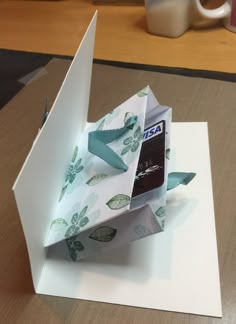 an origami cell phone in a gift bag on top of a card holder