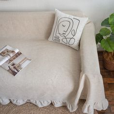 a couch with a pillow on it next to a potted plant