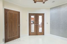 an empty room with two wooden doors and white flooring on the other side of the room