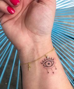 a woman's wrist with an eye and cross tattoo on it