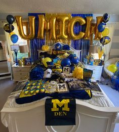 a bed topped with blue and yellow decorations next to a large balloon that says umbc