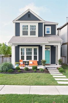 a blue and white house with steps leading up to the front door that lead into the yard