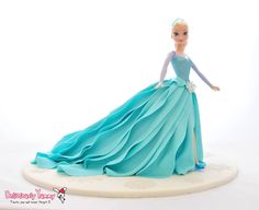 a barbie doll wearing a blue dress on top of a white base with an embellishment