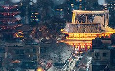 an aerial view of a city at night with lights and buildings in the foreground