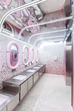 the interior of a public restroom with pink and white decor