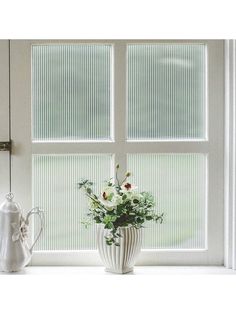 a vase filled with flowers sitting on top of a window sill next to a watering can