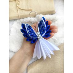 a hand holding a blue and white origami butterfly