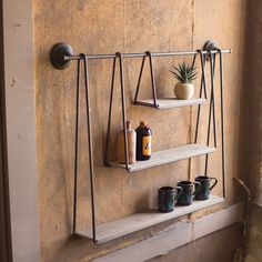 a shelf with three shelves and two cups on it next to a potted plant