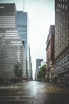 an empty city street with tall buildings on both sides and no cars in the middle