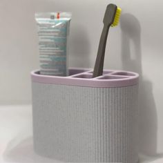 a toothbrush holder with two toothpaste tubes in it