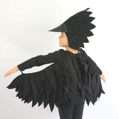 a woman wearing a black bird costume with feathers on her head and hands out to the side