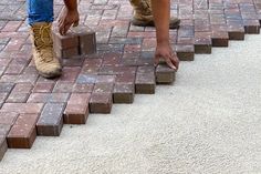 a person standing on top of brick steps with their feet in the ground and one hand reaching down