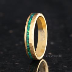 a gold ring with green and blue stones inlayed to the inside of it