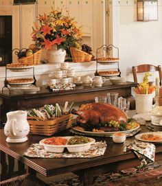 a table full of food and dishes on it with flowers in the centerpieces