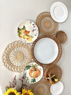 plates and bowls are arranged on a wall with sunflowers in the foreground