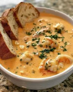 a white bowl filled with shrimp chowee next to a piece of bread on top of a table