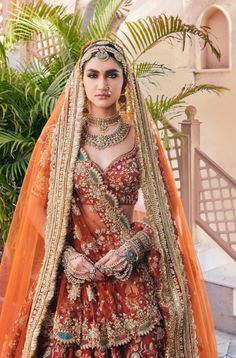 a woman in an orange and gold bridal gown standing next to a palm tree